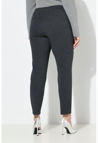 Tummanharmaat slim-fit-housut, jotka on valmistettu kuvioidusta kankaasta. Housuissa on takataskut ja leveä vyötärönauha, yhdistettynä hopeisiin korkokenkiin.