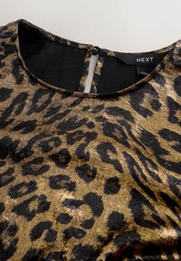 Oberteil mit Leopardenmuster in metallischem Gold und Schwarz, mit Rundhalsausschnitt, Schlüsselöffnungsdetail im Rücken und weichem, strukturiertem Stoff. Etikett sichtbar: NEXT.