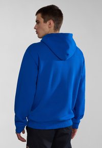 Sudadera con capucha de color azul brillante, con un corte relajado, puños y dobladillo acanalados, y una textura de tela suave. Diseño liso sin patrones.