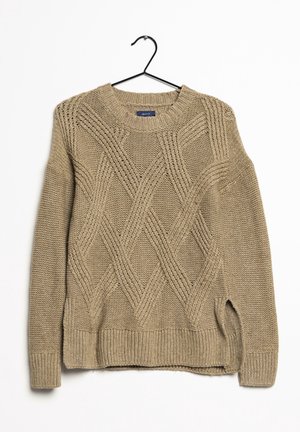 Pull beige en maille torsadée avec manches longues et poignets, ourlet et encolure côtelés, suspendu sur un cintre noir sur fond blanc.