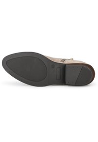 Bottine en suede marron avec une semelle en caoutchouc noir texturé, fermeture éclair sur le côté et un minimalisme dans les détails de la tige.