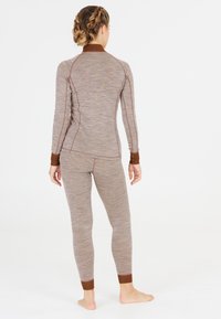Bruine en grijze langetermijn top met bijpassende legging, gemaakt van zachte gebreide stof met contrasterende bruine manchet en naden.