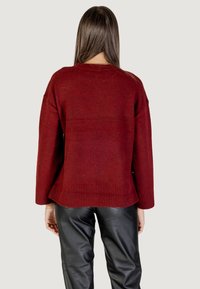 Maglione rosso lavorato a maglia con una vestibilità rilassata, orlo a coste e maniche lunghe. La texture risulta morbida, con un motivo leggermente mélange.