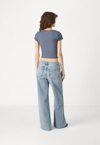 Γκρίζο κοντομάνικο cropped top συνδυασμένο με ανοιχτό μπλε φαρδύ τζιν παντελόνι. Και τα δύο αντικείμενα έχουν ομαλή υφή και απλό σχέδιο.