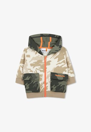 Sweat à capuche camo dans des tons beige et vert, avec une fermeture éclair sur le devant, deux poches avant, un zip orange et une capuche. Marque Timberland sur la poche.