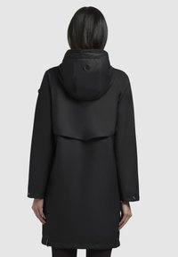 Zwarte waterdichte jas met een nauwsluitende capuchon, lange mouwen, zijzakken en een achterkantflap voor extra ventilatie. Glad, mat textuur.