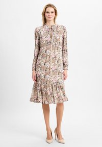 Blumenkleid mit langen Ärmeln, Ausschnitt mit Schlüssellochdetail, Rüschensaum und einer pastellfarbenen Palette mit rosa, grün und braunen Akzenten.