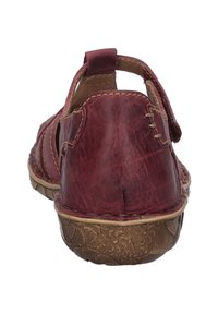 Rote Leder-Sandale mit offenem Rücken, seitlichen Ausschnitten und genähten Details. Strukturierte braune Sohle mit Blumemuster.