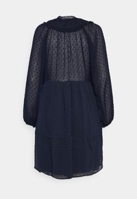 Vestido azul marinho, até ao joelho, feito de tecido transparente com bolinhas texturizadas, decote franzido e mangas volumosas, apresentando uma saia em camadas.
