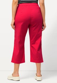 Röda korta byxor med elastisk midja, med en slät textur och en vid benprofil. Matchas med ljusa slipskor.