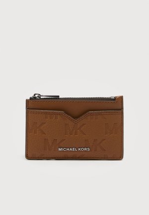 Brauner Kartenhalter von Michael Kors mit geprägt "MK"-Muster, vorderem Kartenfach und oberem Reißverschlussfach auf weißem Hintergrund.