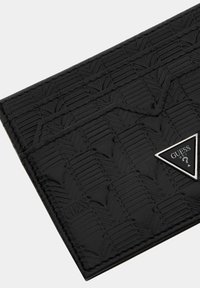 Portefeuille noir texturé avec un motif géométrique, doté d'un accent de logo triangulaire argenté à l'avant. Fabriqué en matériau durable.