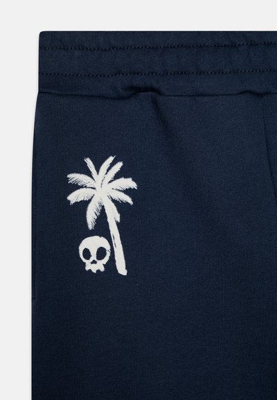 Mörkblå sweatpants med vit palmträd- och döskalletryck. Mjuk tyg med elastisk midja, som har en slät och plan yta.