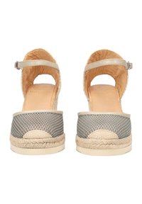 Espadrilles beige de espalda abierta con lados de malla, suelas de yute trenzado y correas en el tobillo ajustables; plantilla de cuero suave con logotipo en relieve.