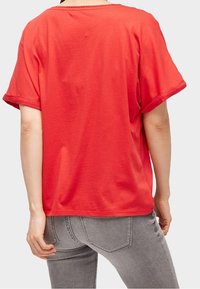 Rød bomulds t-shirt med korte ærmer, en afslappet pasform og en rund halsudskæring. Enkel, ensfarvet med en glat overflade.