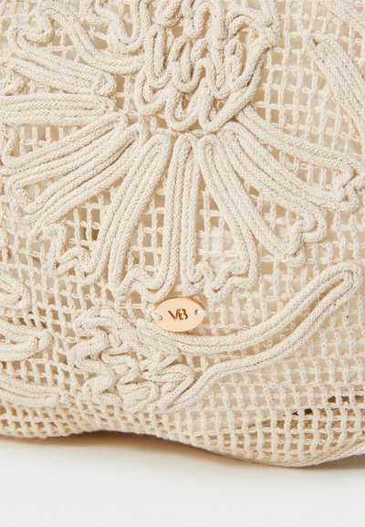 Beige crochet bag featuring intricate floral embroidery, a textured mesh pattern, and a small rose gold metal tag with 'VB' logo.