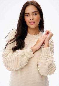 Beige geribde trui met lange, luchtige mouwen. Beschikt over een ronde halslijn en een gestructureerd patroon. Gladde stof met elastische manchetten.