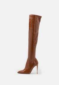 Brązowe błyszczące kozaki do uda z szpiczastym noskiem i obcasem typu stiletto, o bezszwowym designie i minimalnych akcentach.