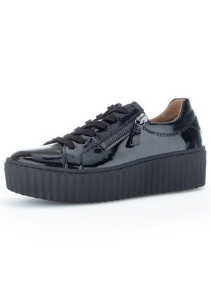 Baskets en cuir verni noir avec des lacets noirs, détail de zip sur le côté et une semelle épaisse à plateforme striée. Texture lisse sur l'ensemble.