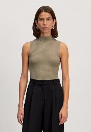 Khaki geribbelde mouwloze top met een hoge hals, gecombineerd met zwarte high-waisted broeken. Soepele textuur en aansluitende pasvorm.