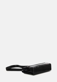 Borsa in vernice nera con forma rettangolare, profilo piatto e manico corto; presenta una superficie testurizzata e un design minimalista.