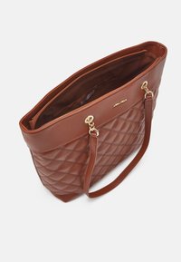 Sac fourre-tout marron matelassé en simili cuir avec fermeture éclair supérieure, deux poignées et accents en matériel doré.