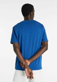 Blå t-shirt med korte ærmer lavet af blødt stof med rund halsudskæring, glat tekstur og lige kant. Ingen synlige grafik eller mønstre.