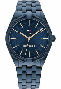 Tommy Hilfiger óra sötétkék fémlánccal és számlappal. Arany órák és mutatók, barázdált keret, valamint zászló logó a közép közelében.