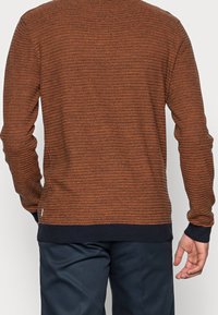 Virkat tröja med horisontella ränder i orange och brunt, med mörk ribbad nederkant och muddar. Mjuk textur, design med rund hals.