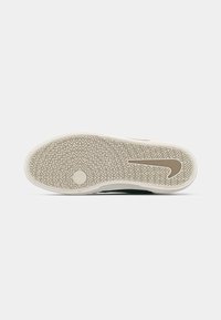 Nike sneaker sole. White rubber with intricate zigzag pattern and star-shaped detail at the center. Beige accents with a swoosh logo.