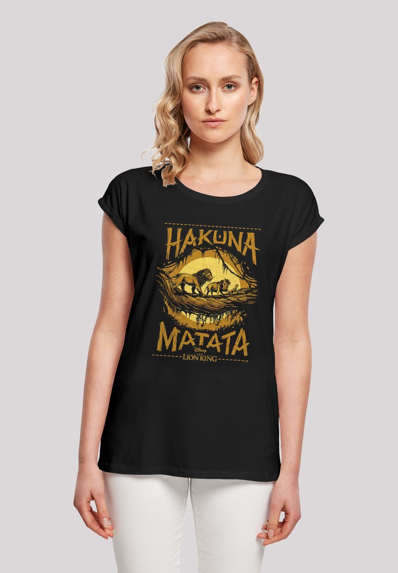 Camiseta negra de manga corta con un estampado gráfico amarillo que presenta "Hakuna Matata" y un diseño de león y cachorro. Tela suave, corte relajado.