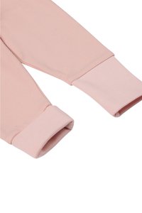 Lichtroze langesleeve top met textured manchetten. De stof is zachte katoen, met een aansluitend ontwerp en contrasterende geribbelde manchetten.