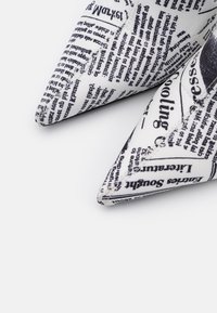 Décolleté con punta, realizzate in tessuto con stampa di giornale bianco e nero. Superficie testurizzata con dettagli di cucitura a contrasto.