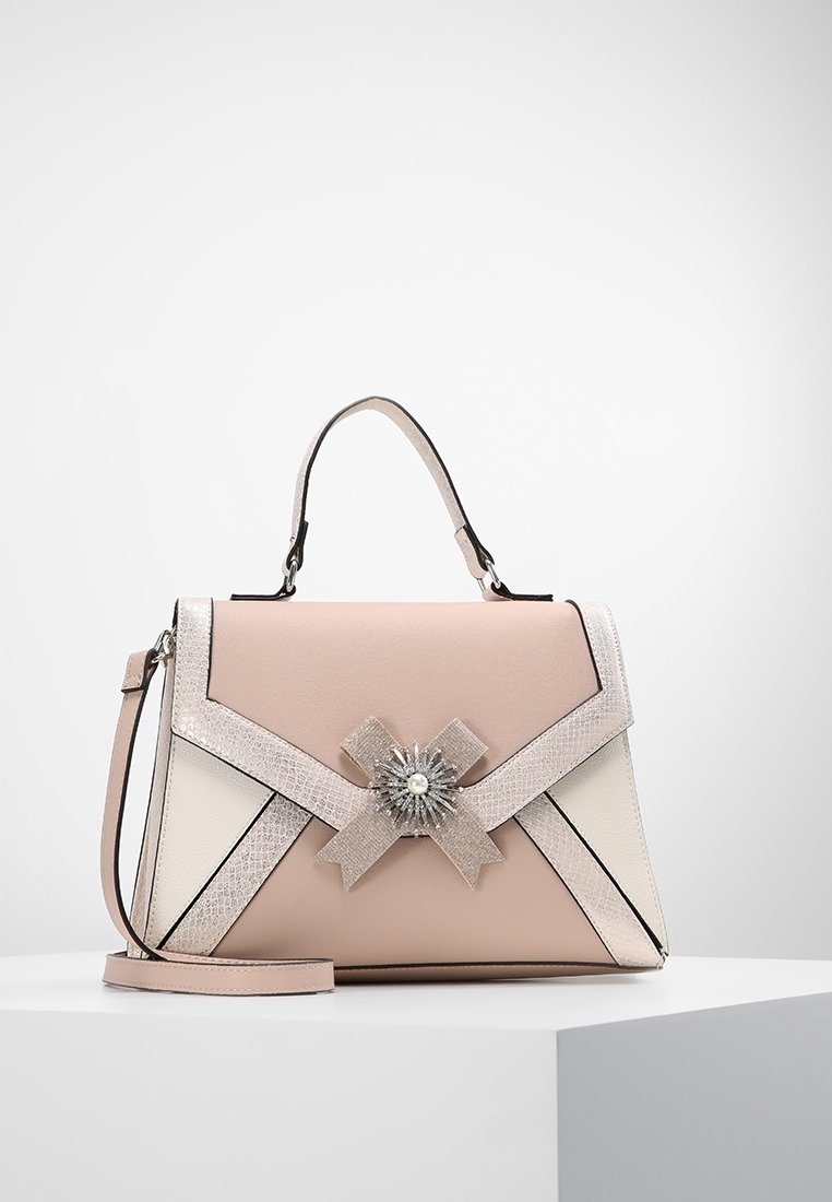 Sac à main rose clair avec un nœud texturé argenté et un centre décoratif orné de bijoux, doté d'une poignée supérieure et d'une bandoulière amovible.