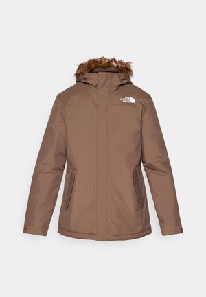 Chaqueta aislante marrón con capucha de pelaje sintético removible, cierre frontal con cremallera, dos bolsillos laterales y un logo blanco en el lado izquierdo del pecho.