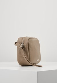 Bežová kožená úložná taška s texturovaným povrchem, obdélníkový tvar, zipový uzávěr a odnímatelný popruh pro všestranné použití.