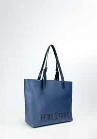Tento námořnický modrý kožený tote bag s texturovaným povrchem má dvojité uchy a na přední straně značka "FEMESTAGE" vytištěná černým písmem.