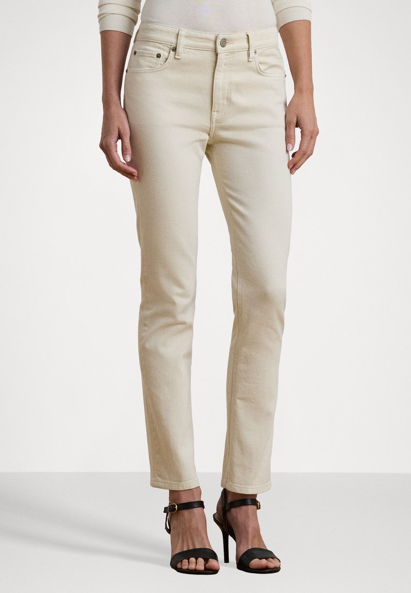 Béžové denimové kalhoty slim fit, klasický pět pocket design, poutka na opasek a zipový zip. Nosit s černými sandály na vysokém podpatku s pásky.