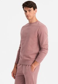 Hellrosa Sweatshirt aus weichem Stoff, mit Rundhals, gerippten Bündchen und glatter Textur. In entspannter Passform gestaltet.