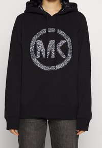 Black hoodie featuring a gray leopard-print MK logo in a circular design. Soft fabric, long sleeves, and adjustable drawstring hood.