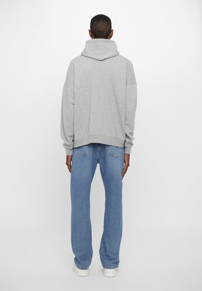 Grauer Kapuzenpullover mit lockerer Passform, gerippten Bündchen und Saum. Kombiniert mit hellblauen, geraden Jeans und weißen Sneakers.