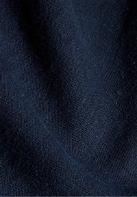 Tessuto blu scuro con una consistenza liscia, caratterizzato da un delicato motivo a trama, che indica un materiale di peso medio, adatto per indumenti.