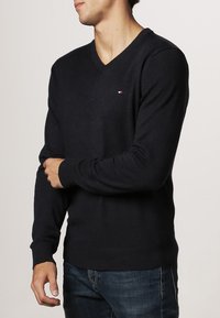 Pull à col en V en mélange de laine bleu marine foncé, avec un petit logo brodé sur la poitrine, des poignets côtelés et une coupe décontractée.