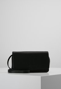 Czarna skórzana kopertówka z klapą na zgięciu, odpinanym paskiem na ramię i gładką fakturą. Minimalistyczny design z subtelnym logo.