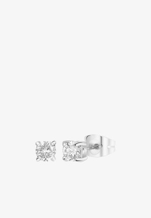 Deux boucles d'oreilles en argent avec des pierres de zircon cubique rondes et transparentes, chacune sertie dans un design à quatre griffes. Une boucle d'oreille est légèrement plus grande.