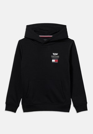 Črna jopa z dolgimi rokavi in sprednjim žepom, z logotipi ekipe Cadillac Formula 1 in Tommy Hilfiger na levi strani prsnega koša.