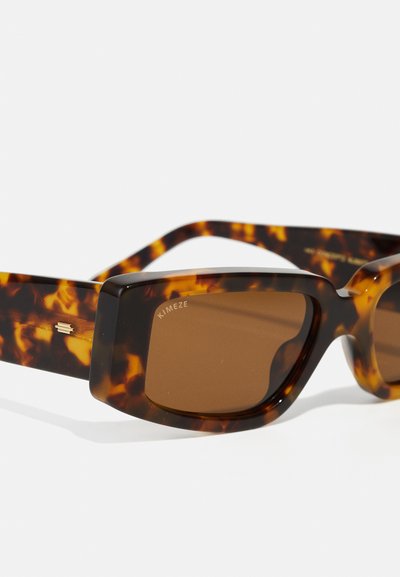 Tortoiseshell sunglasses with thick frames and brown lenses. Design features a square shape and subtle logo detail on the side.