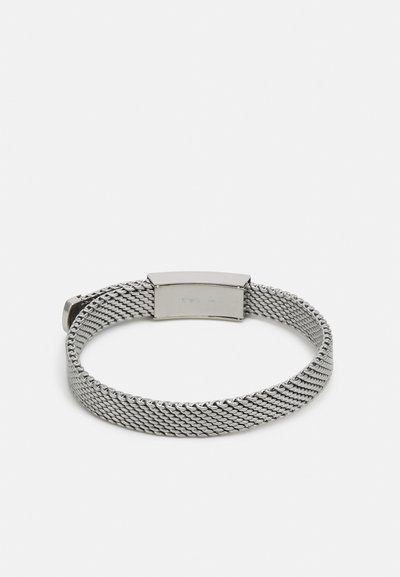 Bracciale in rete argentata con una chiusura in metallo liscio. Presenta un design intrecciato, uno spessore uniforme e una finitura lucida.