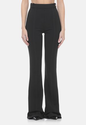 Schwarze, hoch taillierte Glockenhosen mit Vordernaht-Details, getragen von einer Person vor weißem Hintergrund.