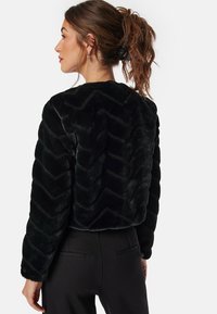 Zwarte nepbont bomberjack met een chevronpatroon, cropped ontwerp en slim fit. Heeft een zachte textuur en een ronde halslijn.